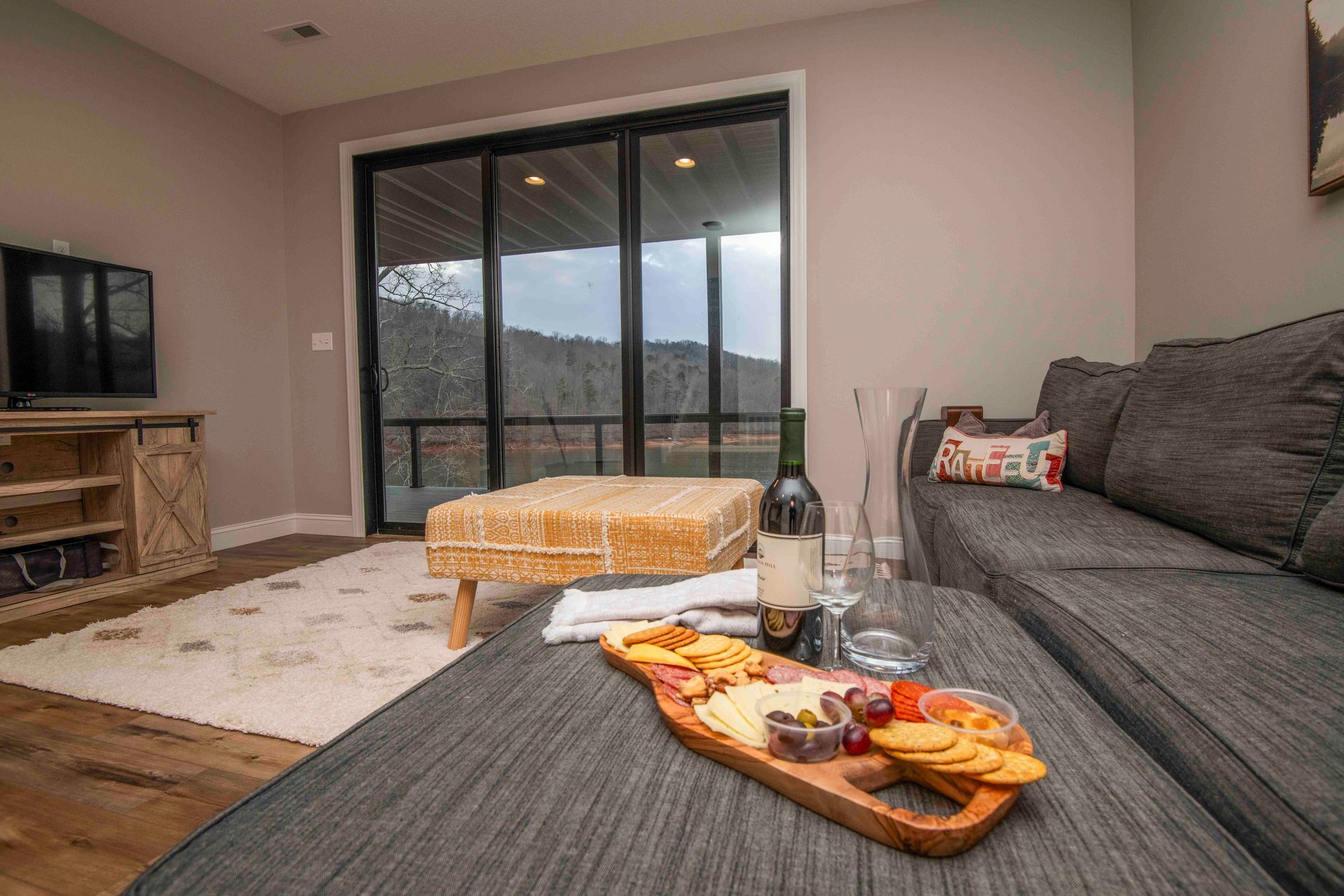 Living room with charcuterie board, wine, and a view of nature from sliding doors.