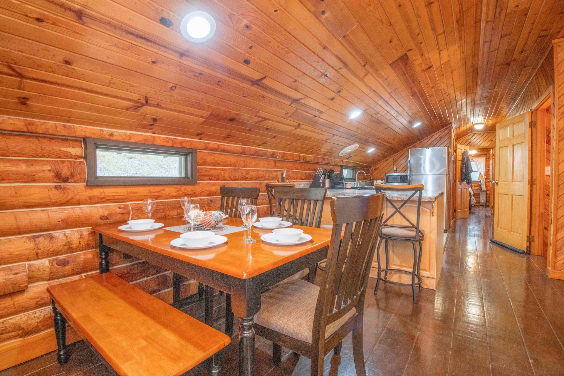 Dining area in a log cabin with a table set for a meal and a small window.