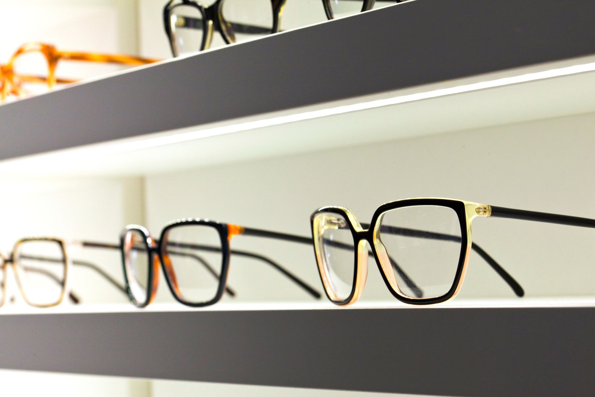 Plusieurs paires de lunettes de vue posées sur des étagères