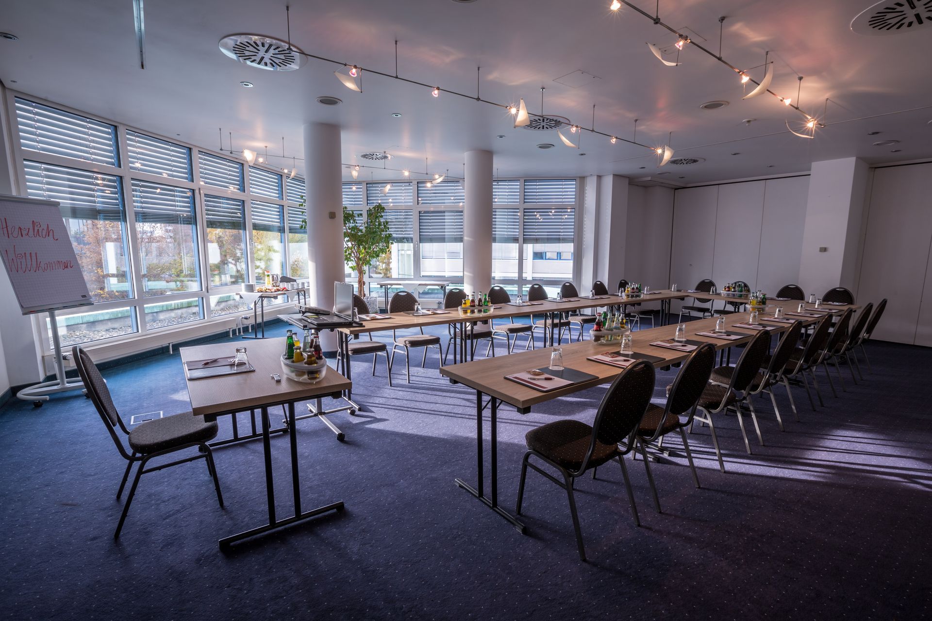 Moderner Konferenzraum mit Tischen, Stühlen und großen Fenstern mit Blick auf die Stadt