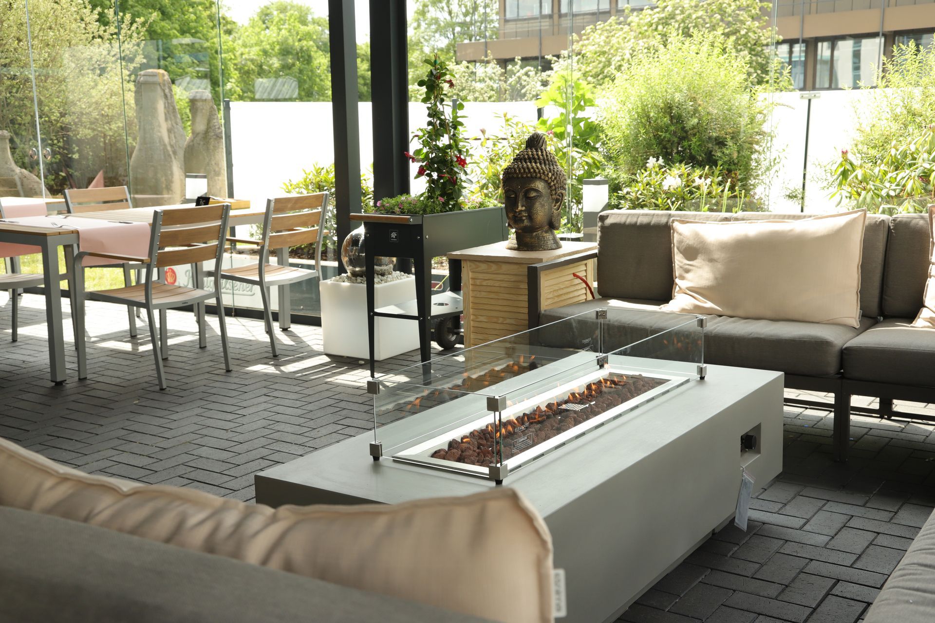 Lounge-Bereich auf der Terrasse mit Sofas, Tischen und Feuerstelle in einem modernen Gartenambiente
