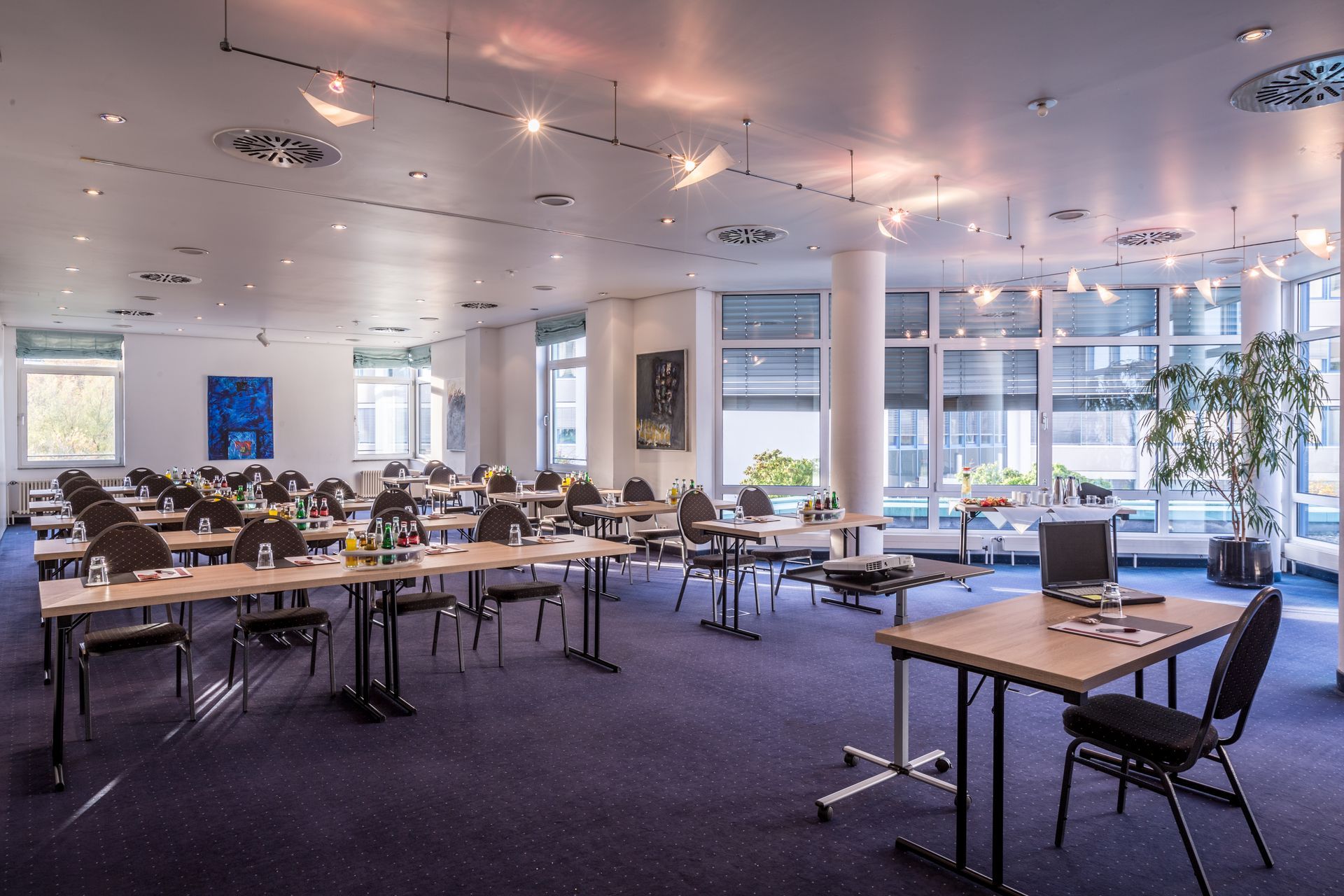 Heller Konferenzraum mit Tischen, Stühlen, Fenstern und Deckenleuchten in einem modernen Büroambiente