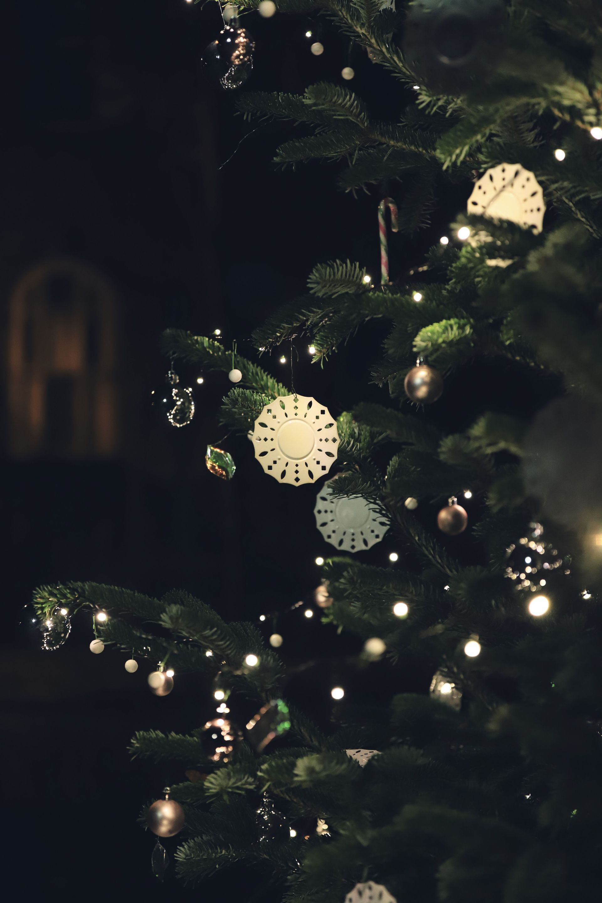 Beleuchteter Weihnachtsbaum mit warmweißen Lichtern und goldenen Kugeln in einem dunklen Raum
