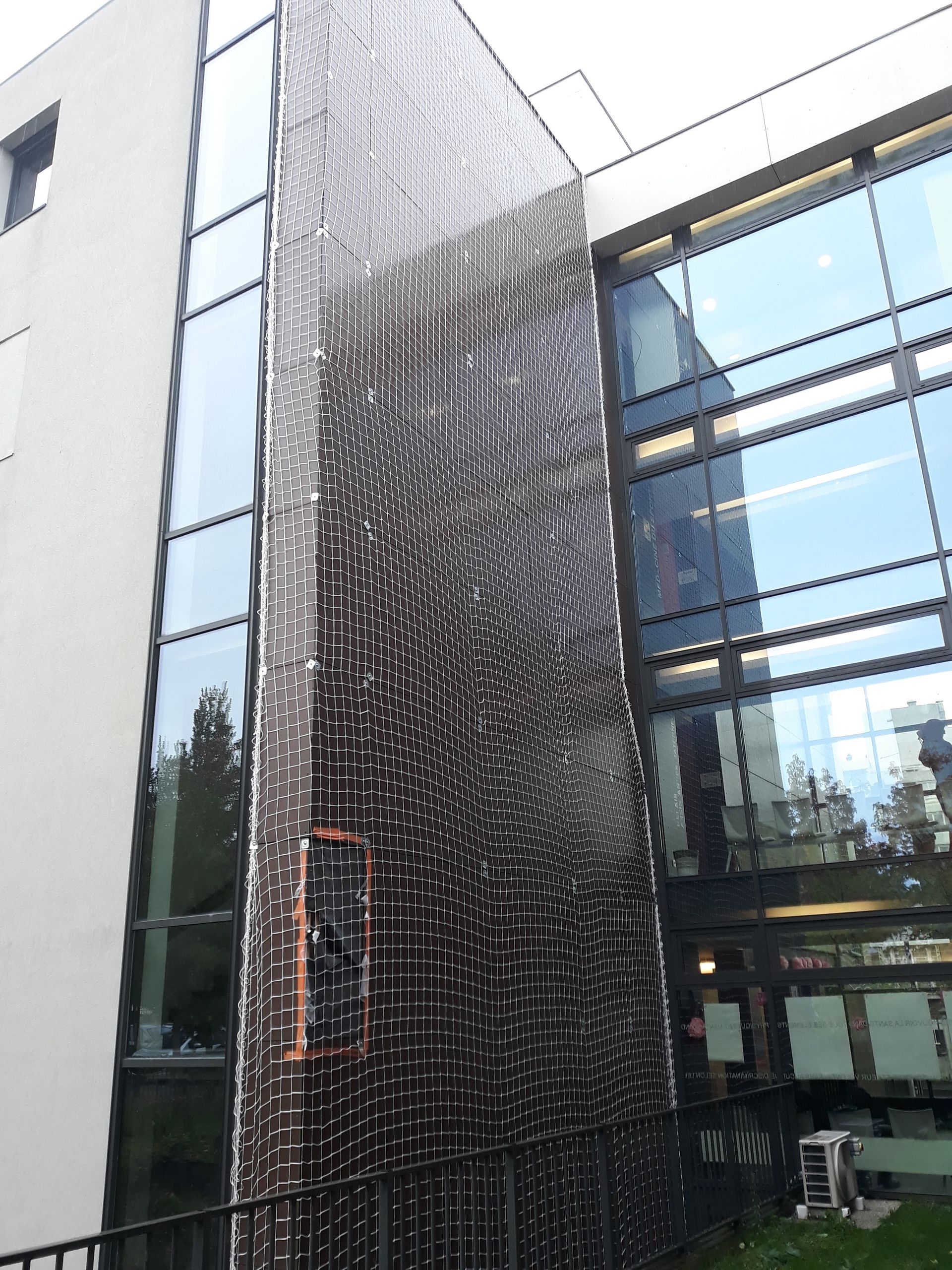 Filet anti-volatiles sur façade de bâtiment.