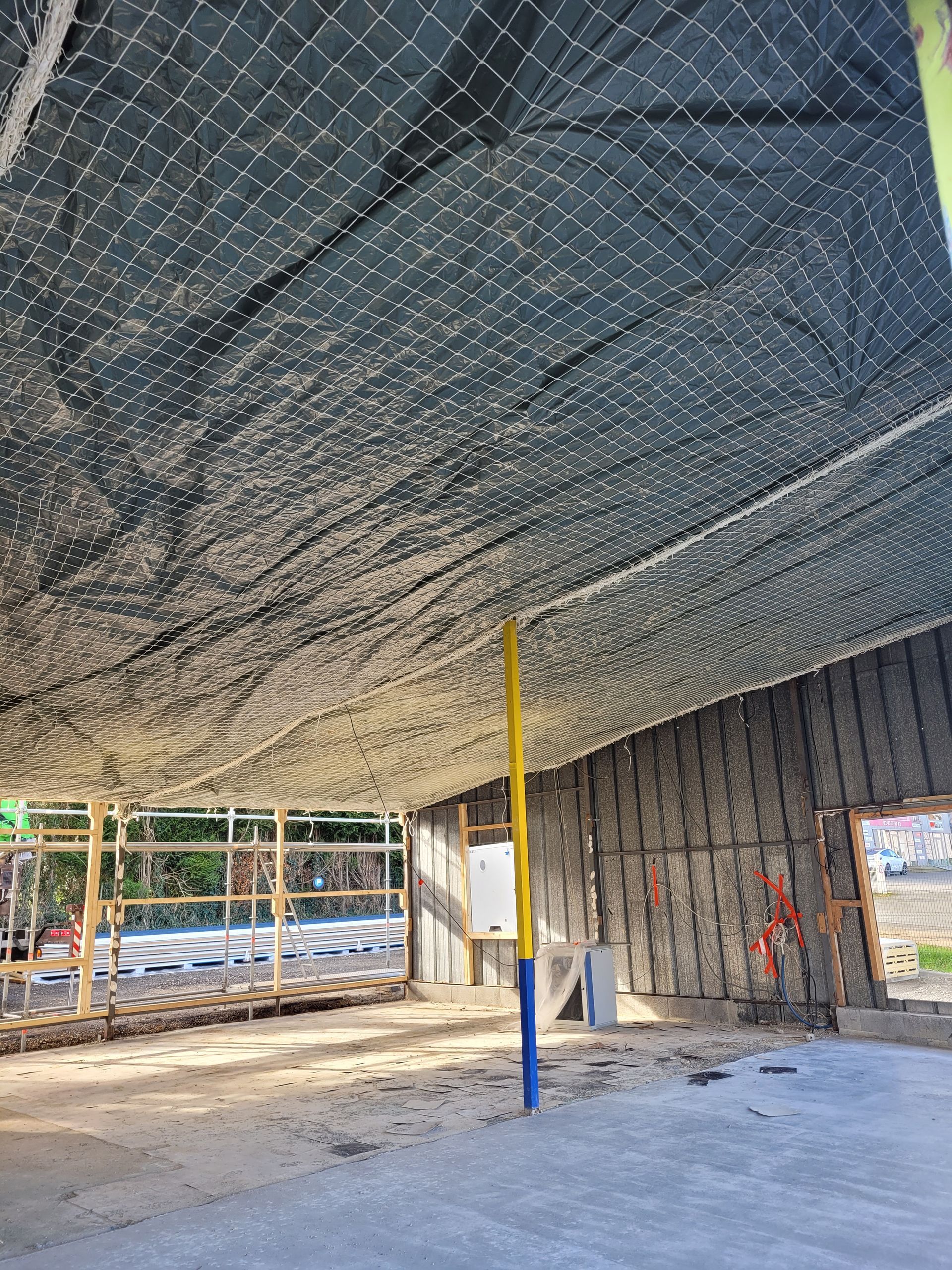 Auvent protégé par un filet anti-volatiles blanc.