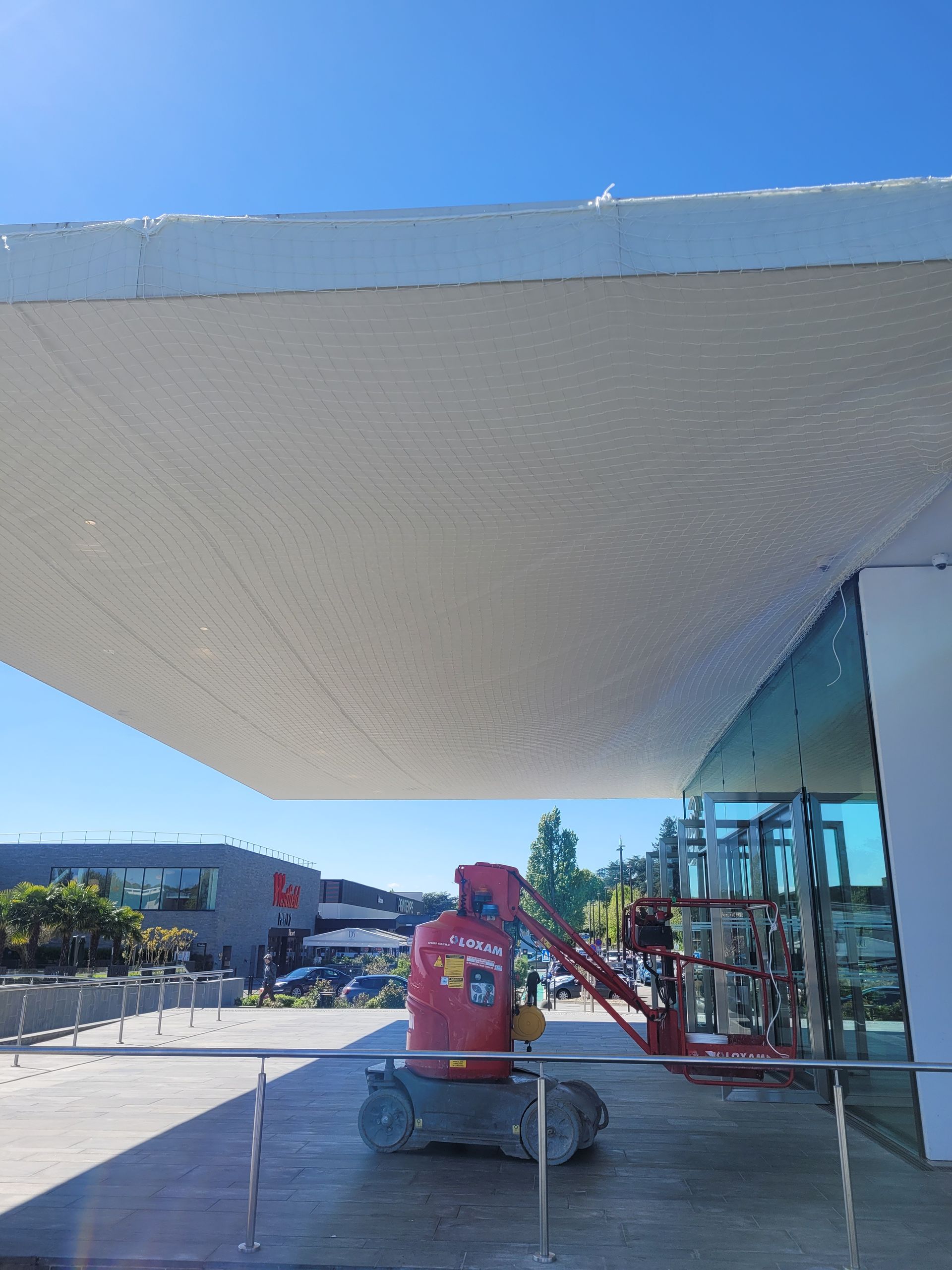 Un filet de sécurité sous l'auvent d'un bâtiment blanc.