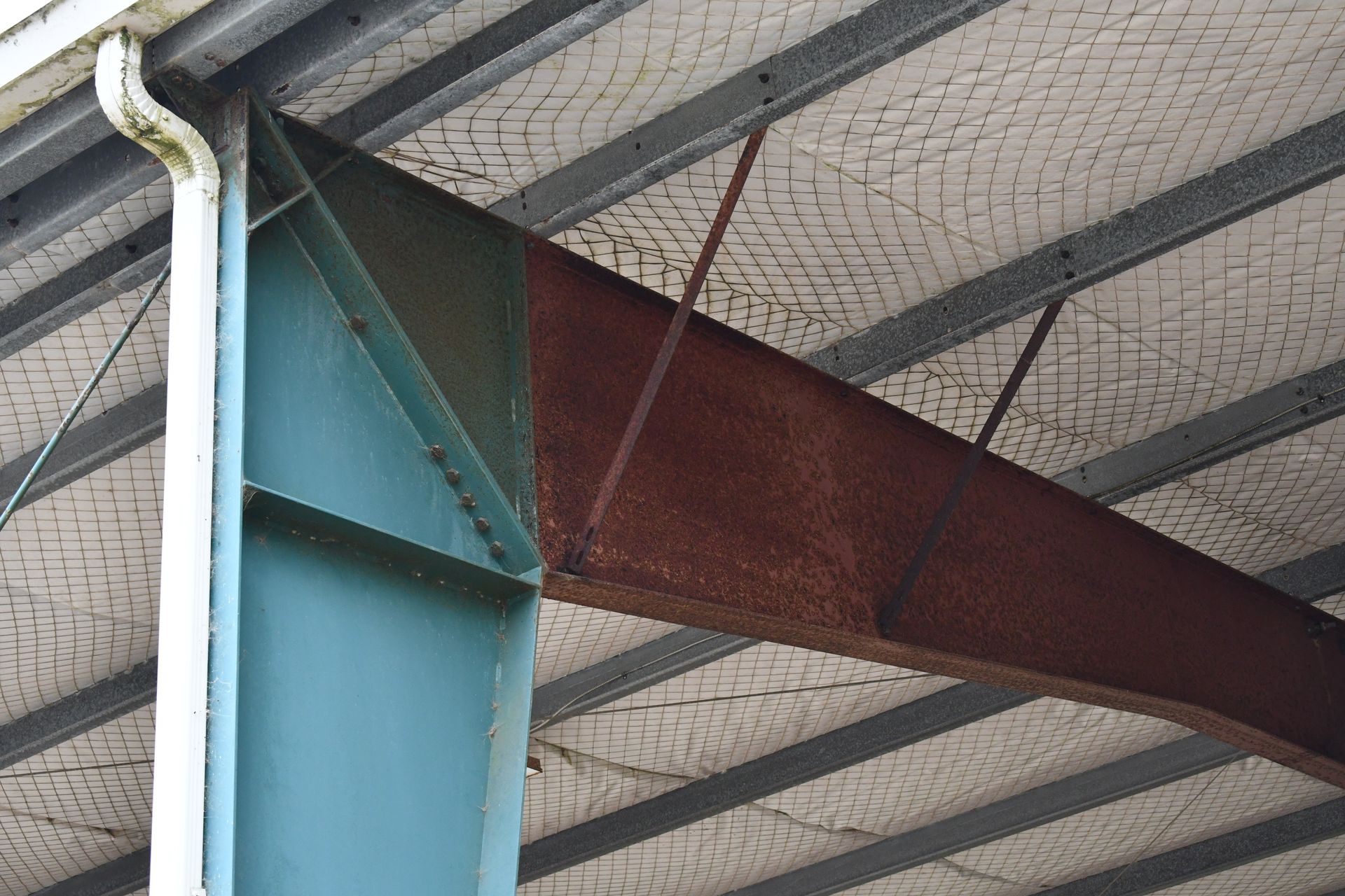 Poutres de soutien métalliques vertes et rouille pour le bâtiment avec filets de sécurité.