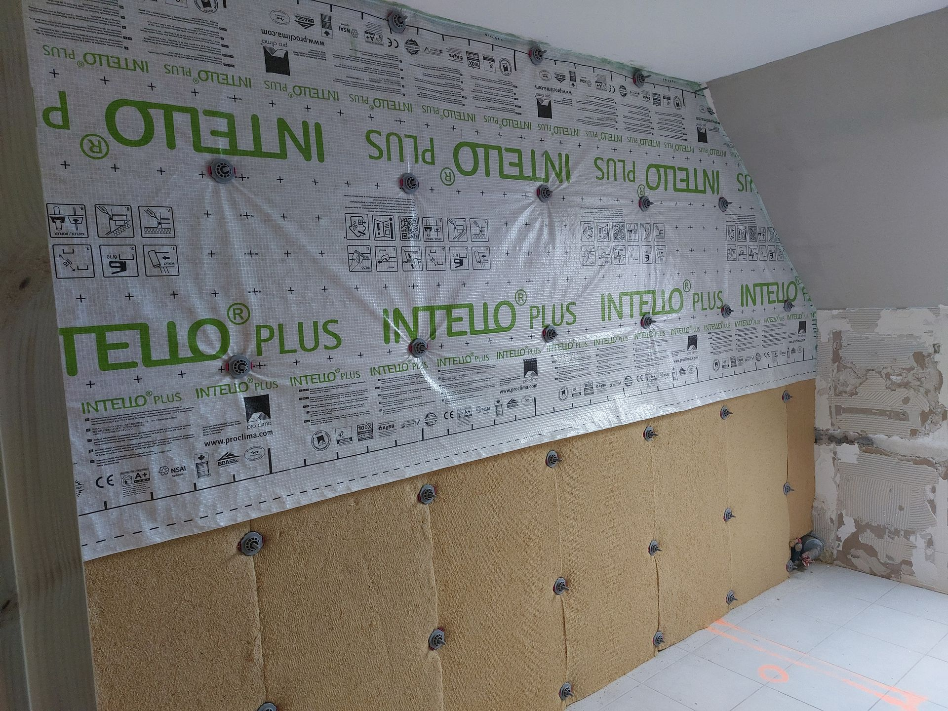 Construction de murs avec isolation, pare-vapeur et panneaux de fibres de bois installés.