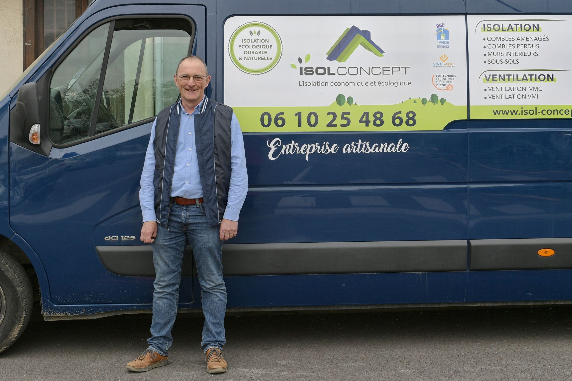 Un homme se tient devant une camionnette bleue portant le logo ISOLCONCEPT et un numéro de téléphone.