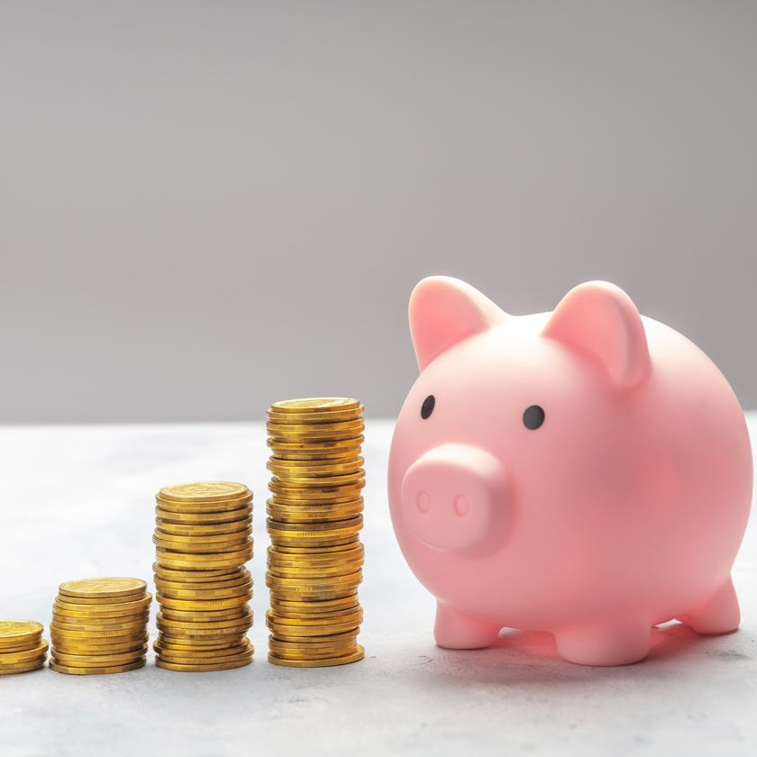 Une tirelire à côté de piles de pièces d'or de hauteur croissante, représentant l'épargne.