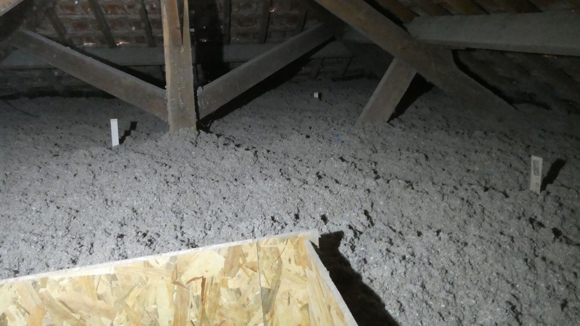 Combles avec isolation grise entre les poutres en bois et le contreplaqué.