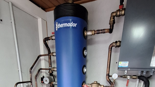 Chauffe-eau Thermador bleu avec tuyaux en cuivre, dans une buanderie.