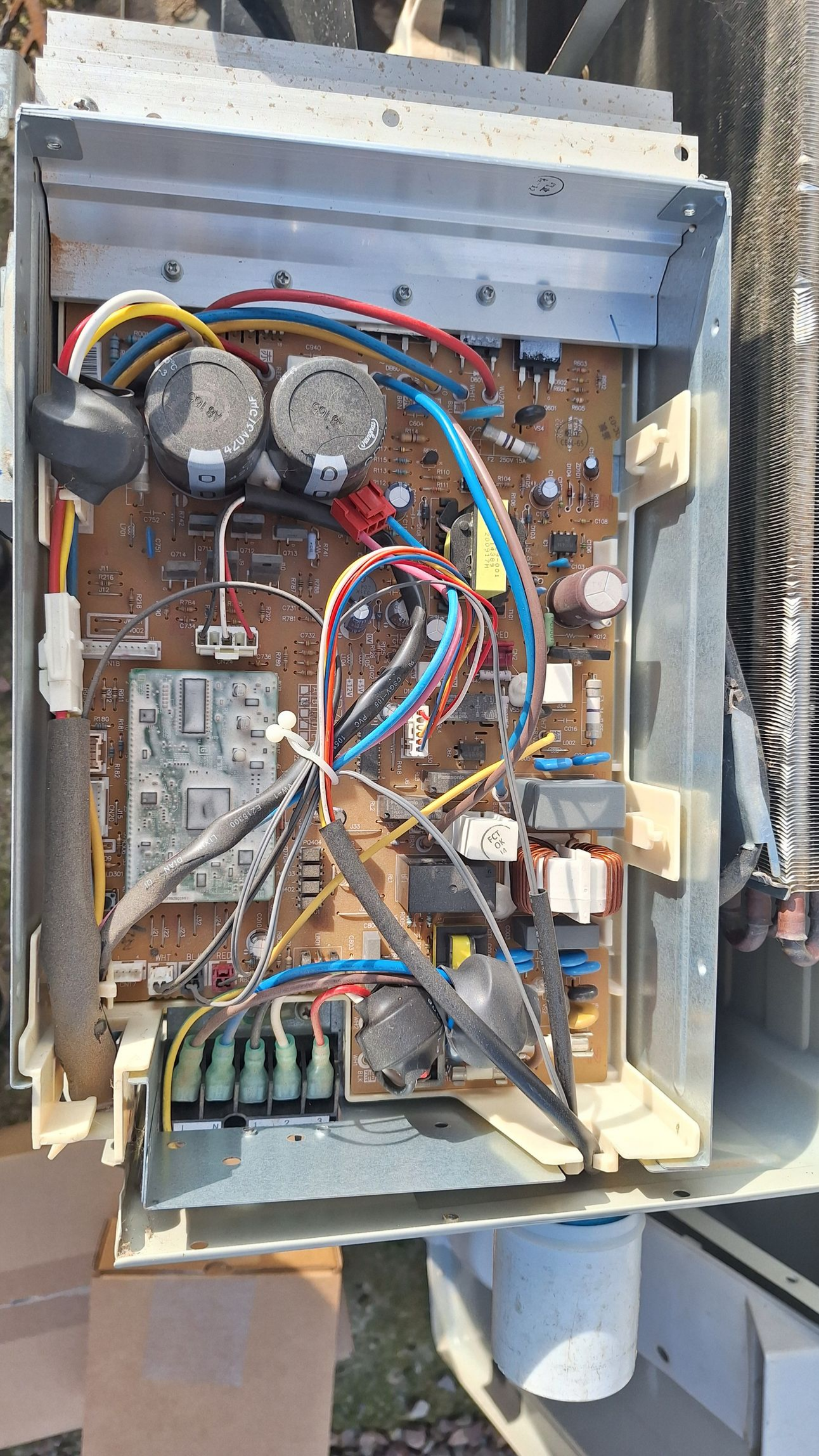 Circuit imprimé ouvert avec fils et composants à l'intérieur d'un boîtier métallique.