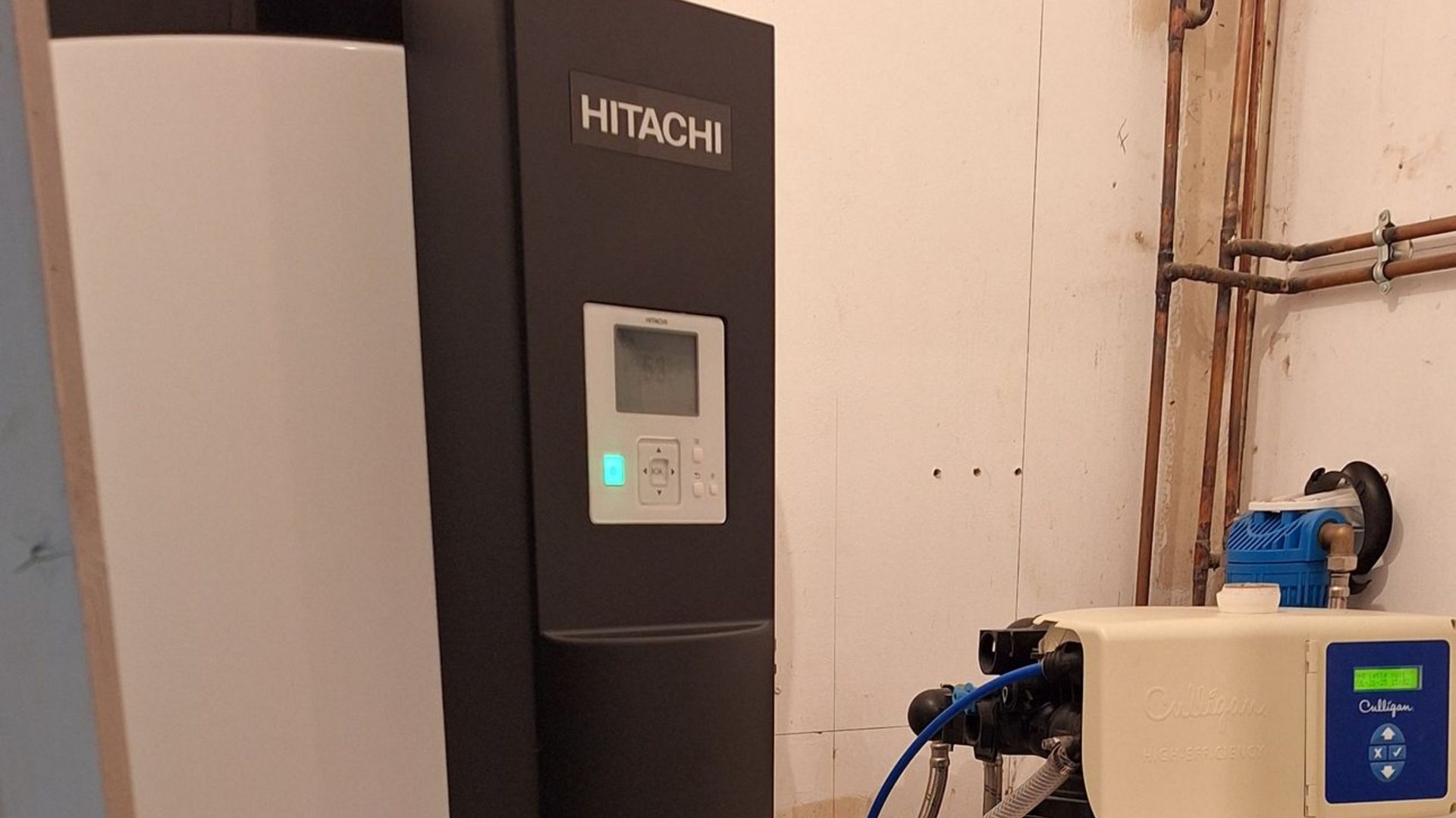 Un système de pompe à chaleur Hitachi dans une pièce avec des tuyaux en cuivre.