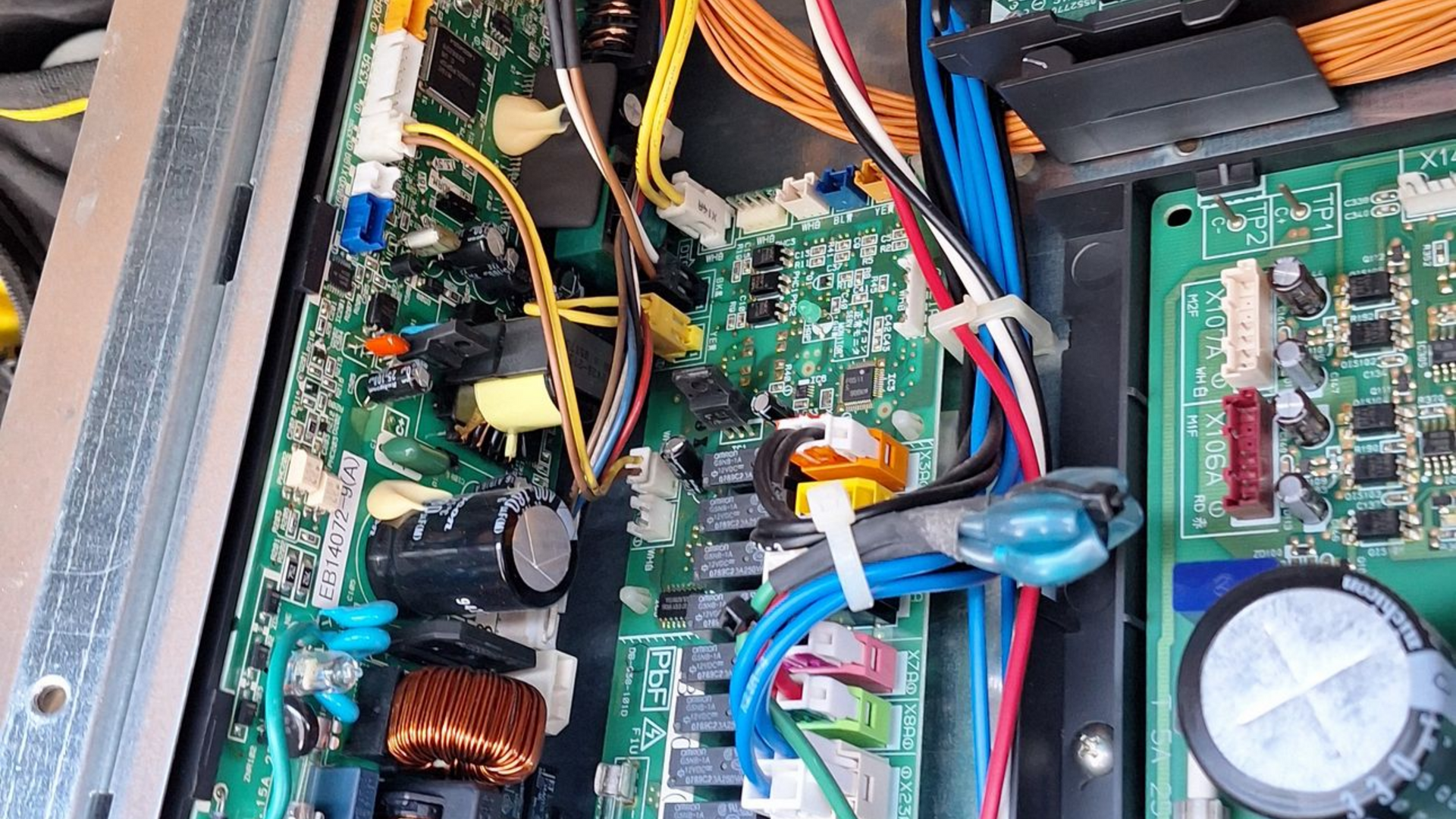 Carte de circuit électronique avec fils et composants à l'intérieur d'un boîtier métallique.