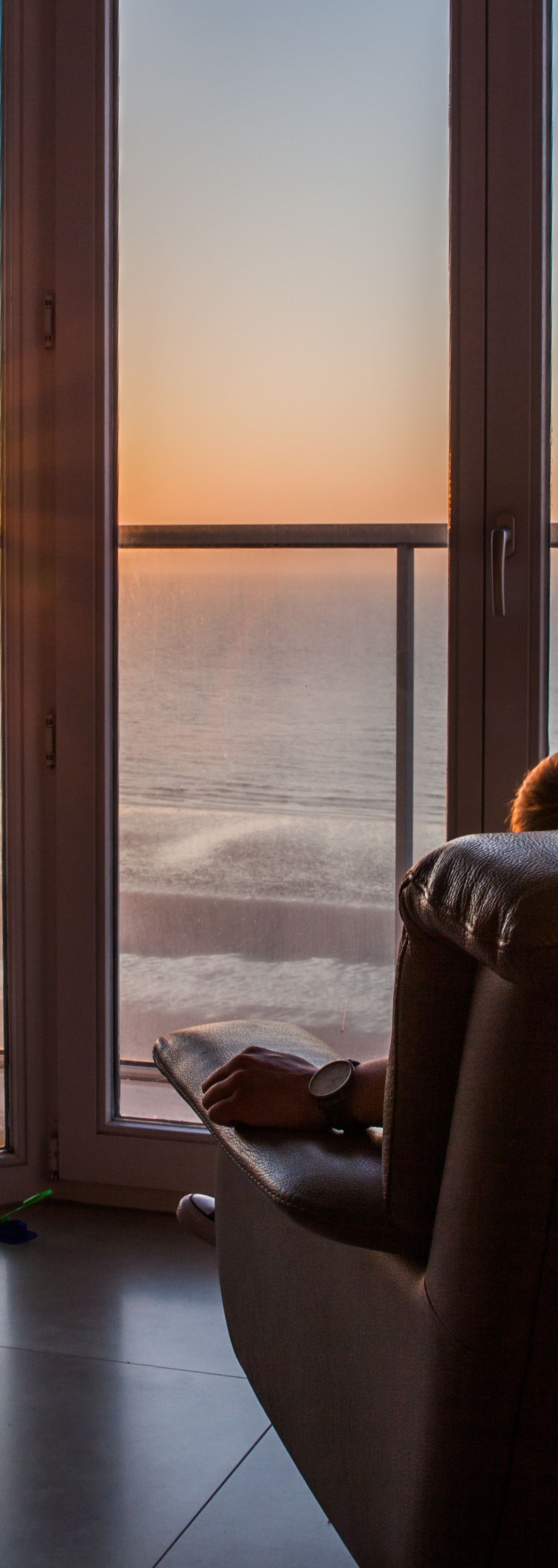 Une vue sur l'océan à travers une fenêtre, depuis un fauteuil confortable.