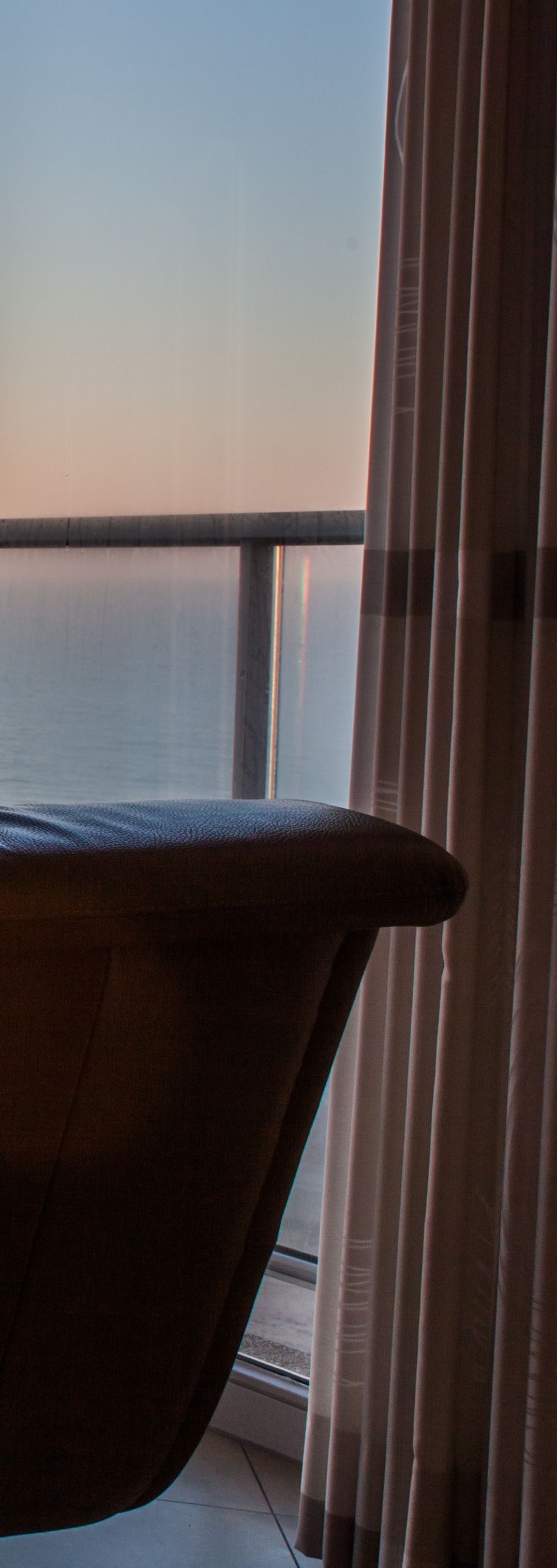 Un fauteuil près d'une fenêtre, avec vue sur l'océan.