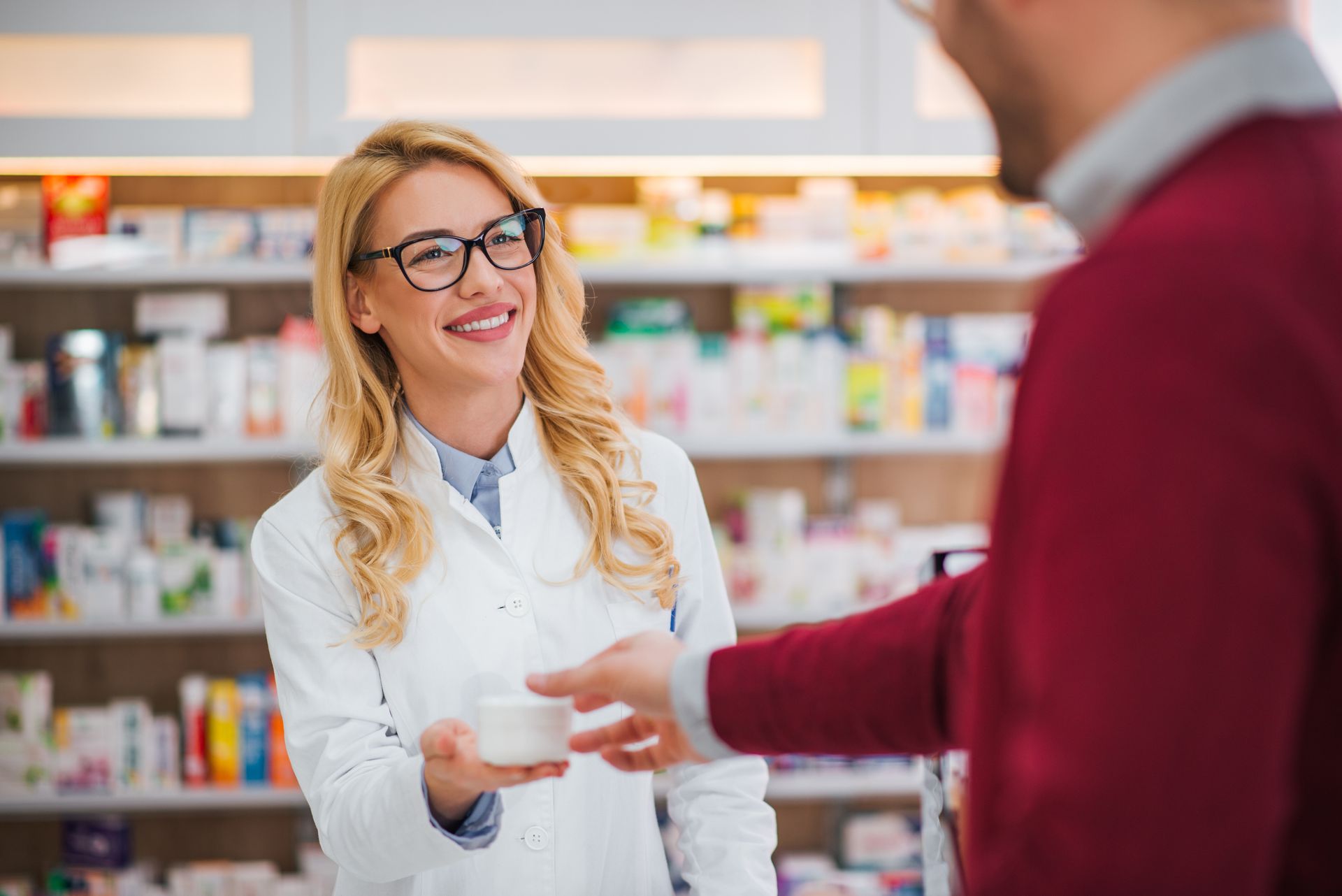 Pharmacienne souriante tendant un produit à un client