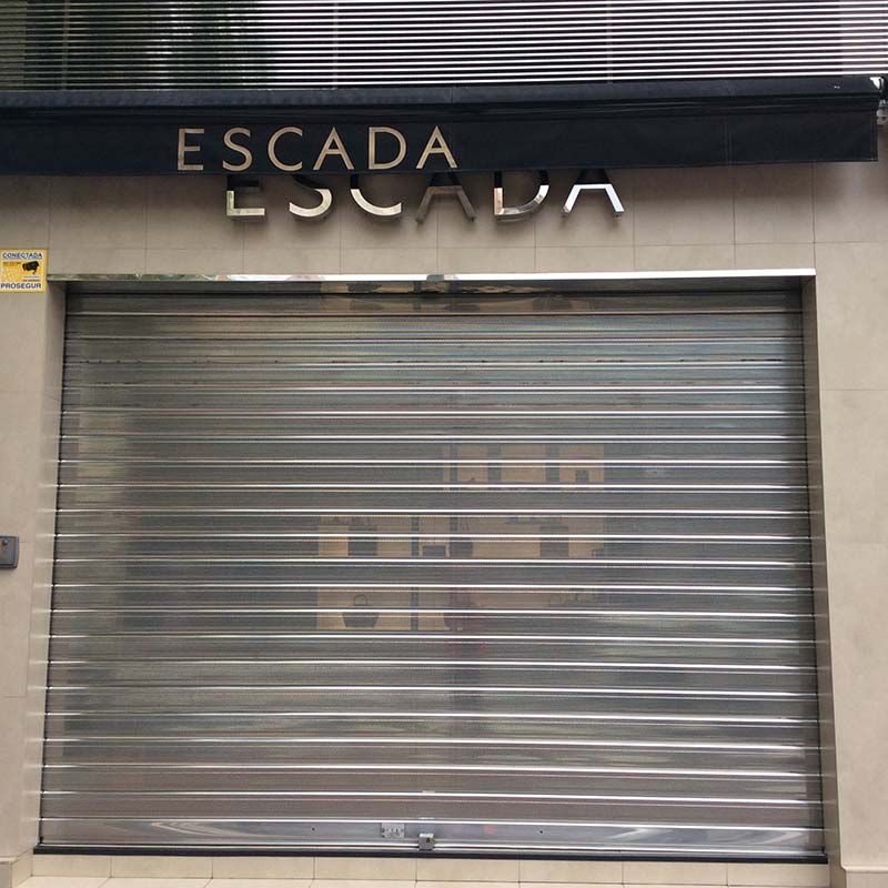 Local comercial cerrado de Escada con persiana metálica y letrero iluminado sobre la entrada.