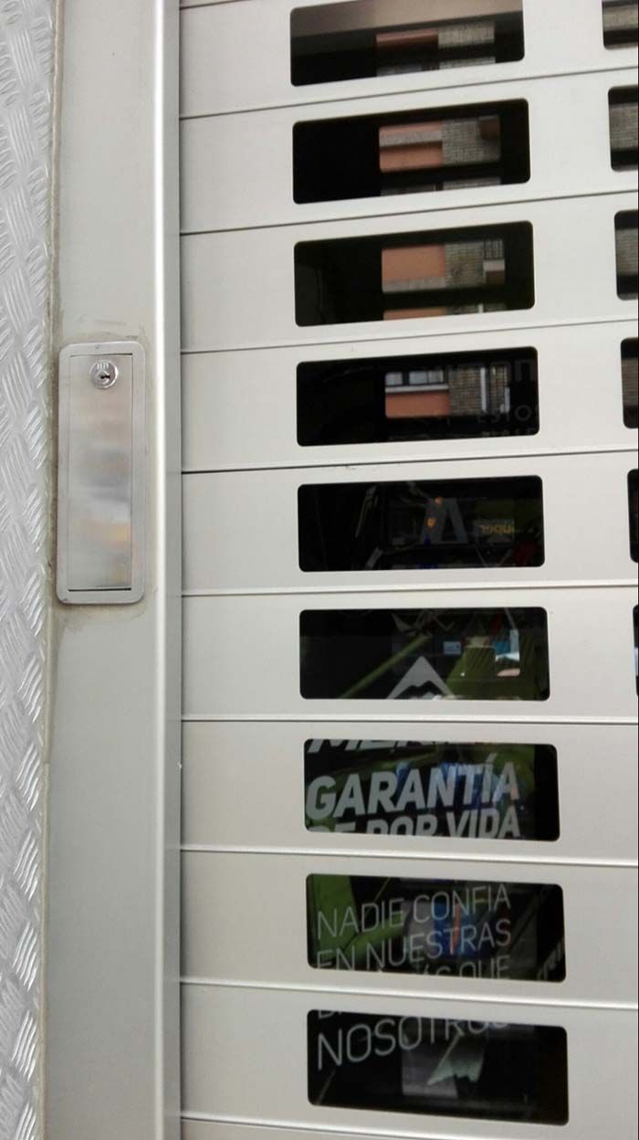 Buzones de metal blanco, algunos con la etiqueta “GARANTÍA”, instalados junto a una puerta o pared.