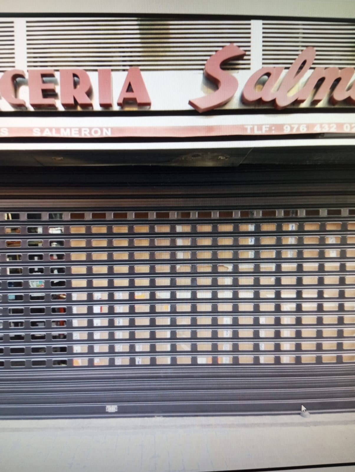 Puerta de garaje marrón cerrada en una pared exterior beige.