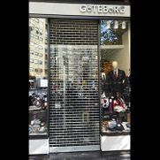 Escaparate cerrado con persiana metálica de seguridad y maniquíes que exhiben zapatos en el escaparate.