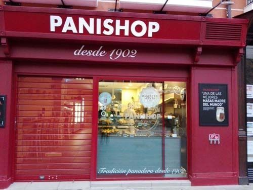 Fachada roja de la panadería PANISHOP con escaparate y letrero “desde 1909”.