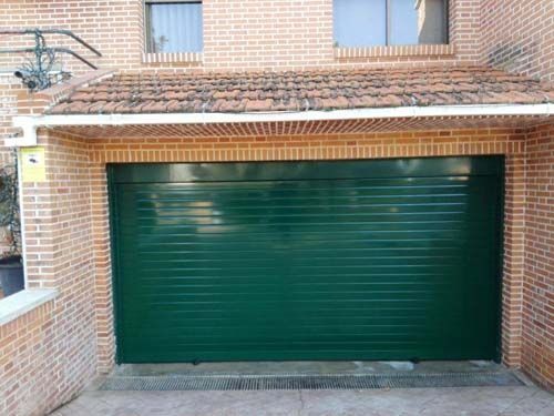 Puerta de garaje verde en el exterior de una casa de ladrillo