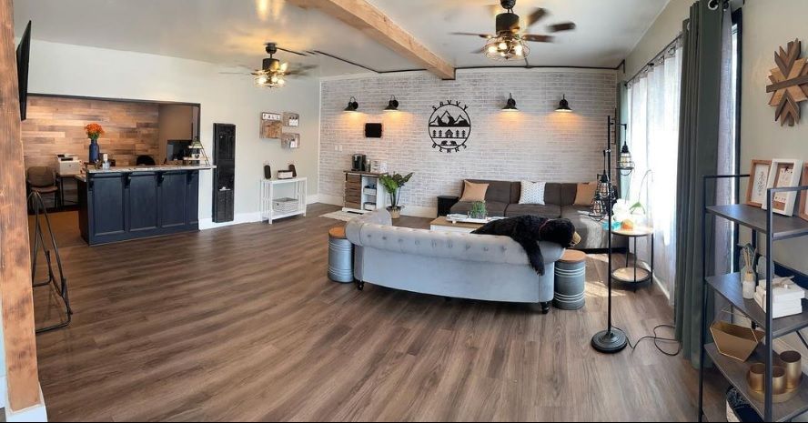 Open-concept room with wood floors, exposed beams, a seating area, and a reception desk.