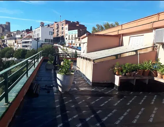 Un balcón con plantas en macetas y vista a una ciudad.