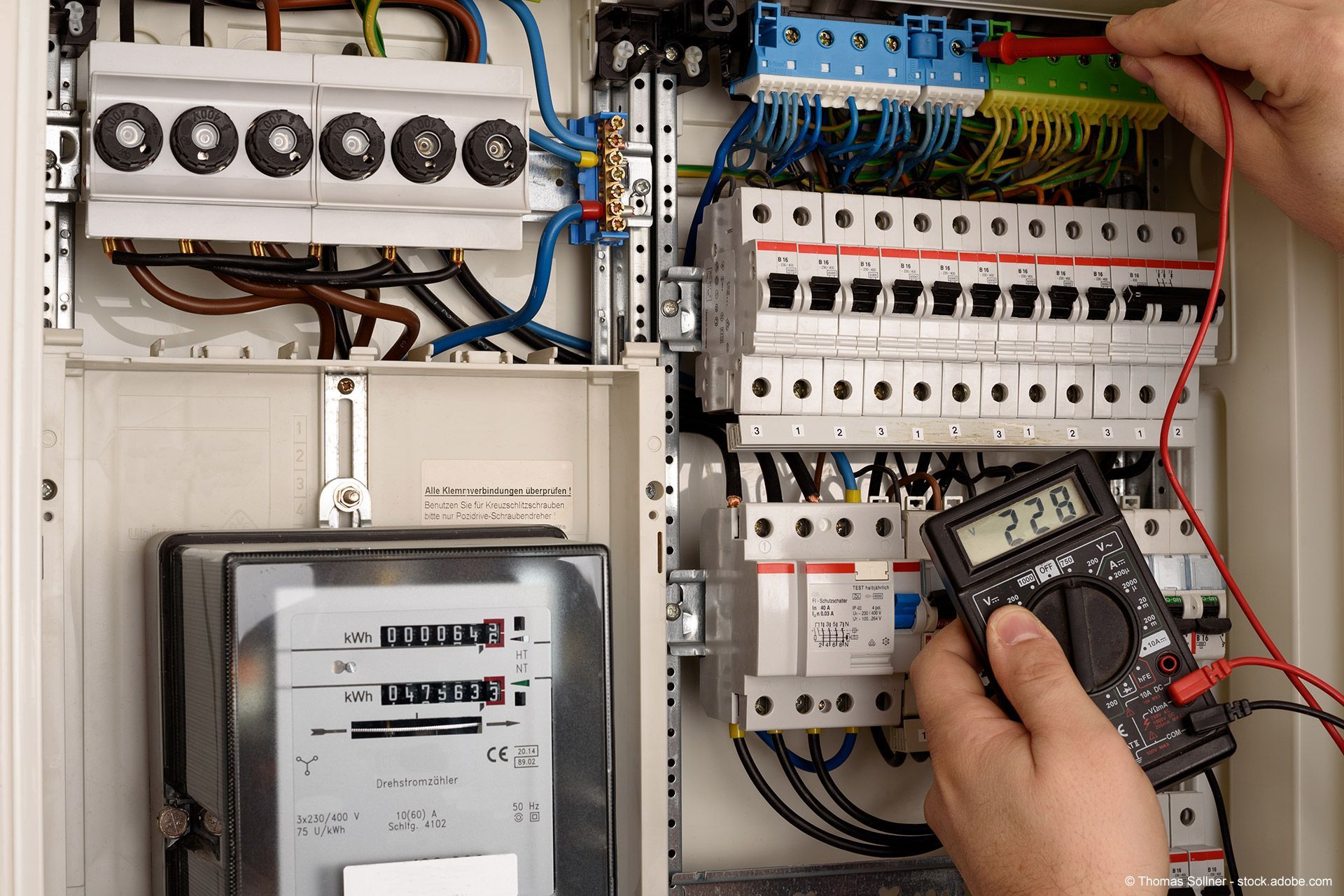 Elektriker prüft die Spannung in einem Schaltschrank mit einem Multimeter.