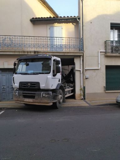 Camion blanc stationné devant l'entrée d'un immeuble