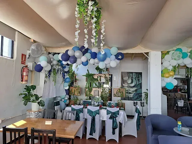 Una habitación con mesas y sillas y globos colgando del techo.