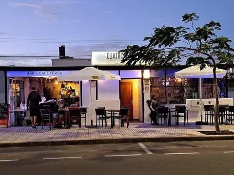 La gente está sentada en mesas afuera de un restaurante llamado Cuarteto.