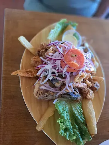 Un plato de comida con patatas fritas y lechuga sobre una mesa de madera.