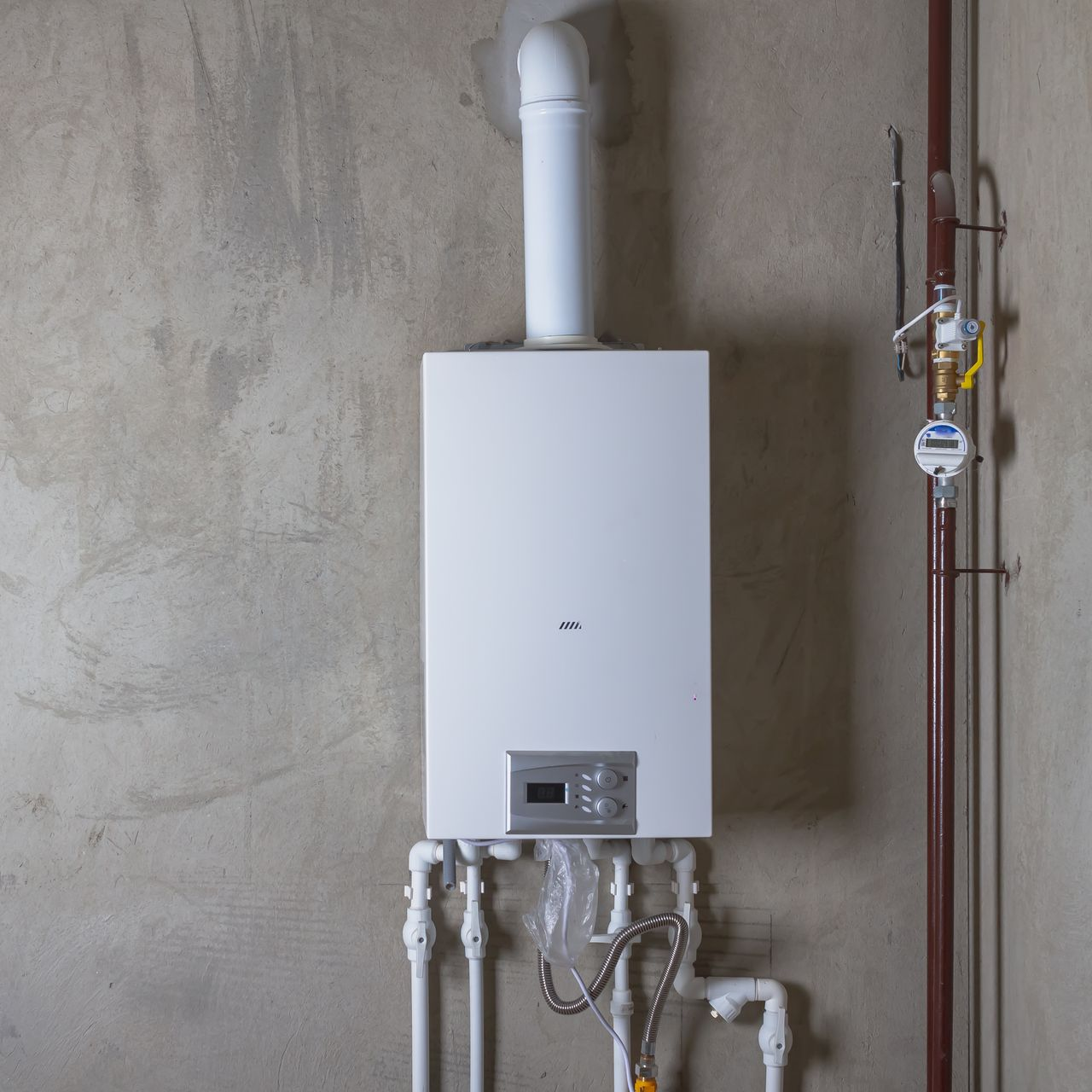 Chaudière à gaz blanche murale avec tuyaux apparents.
