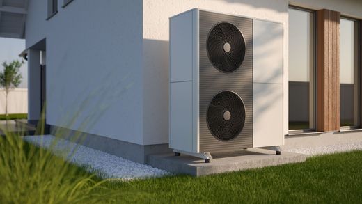 Pompe à chaleur air-eau avec double ventilateur, installée sur une dalle en béton le long de la façade d’une habitation.