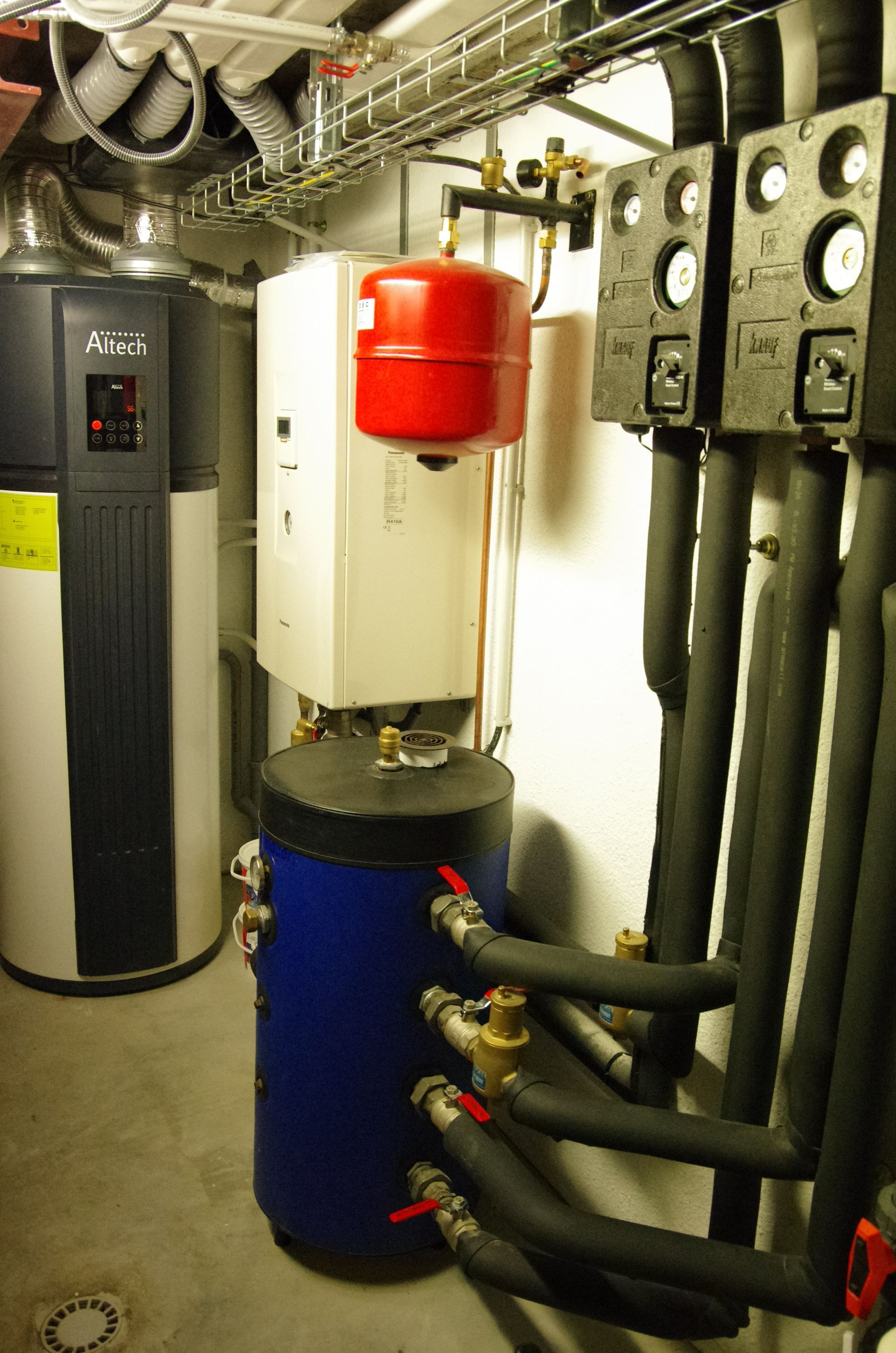 Installation de chauffage comprenant un ballon tampon, un vase d’expansion et un réseau de tuyauteries isolées dans un local technique.