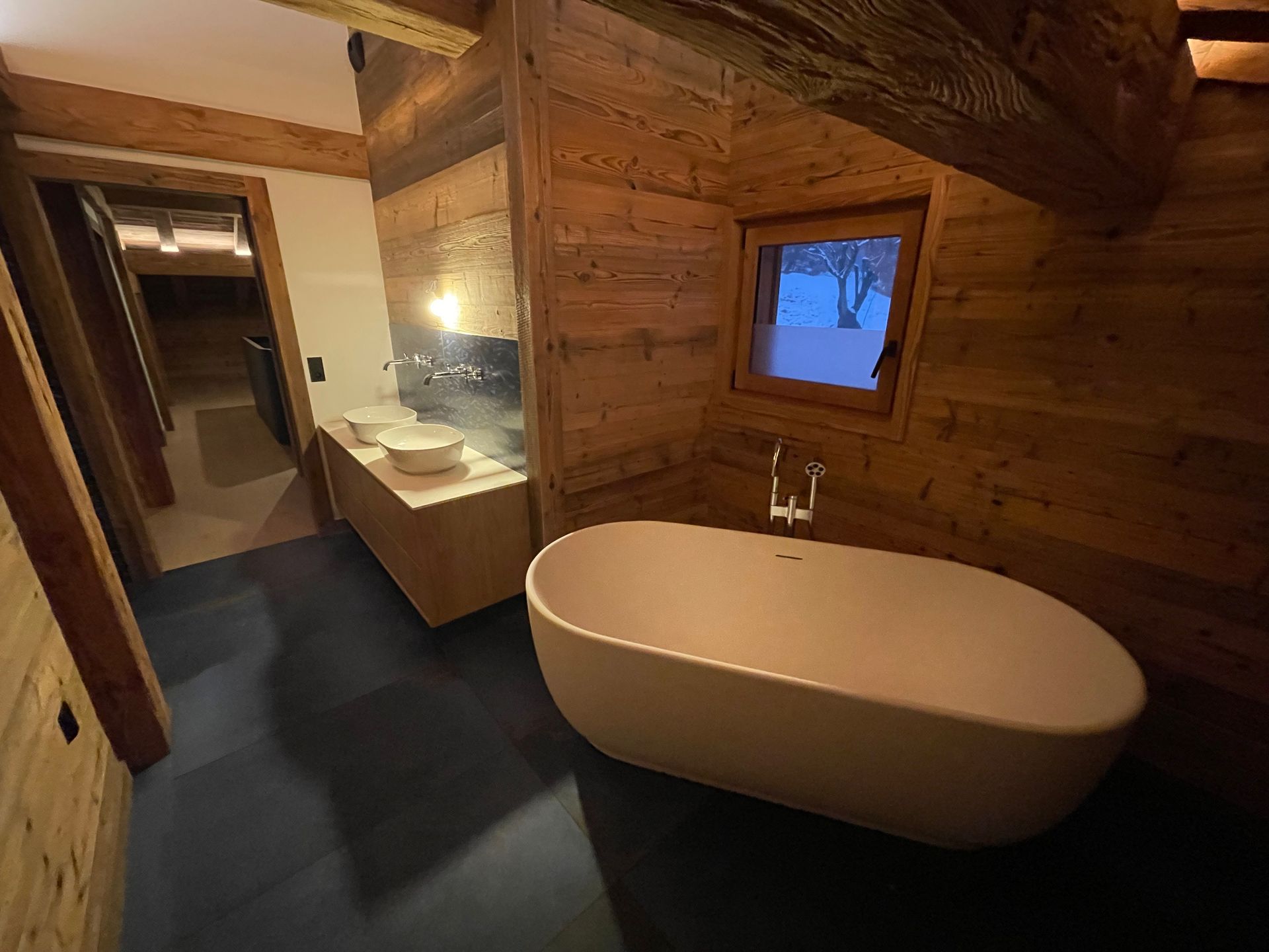 Salle de bains mansardée avec lambris, baignoire îlot, lavabo, meuble double vasque.