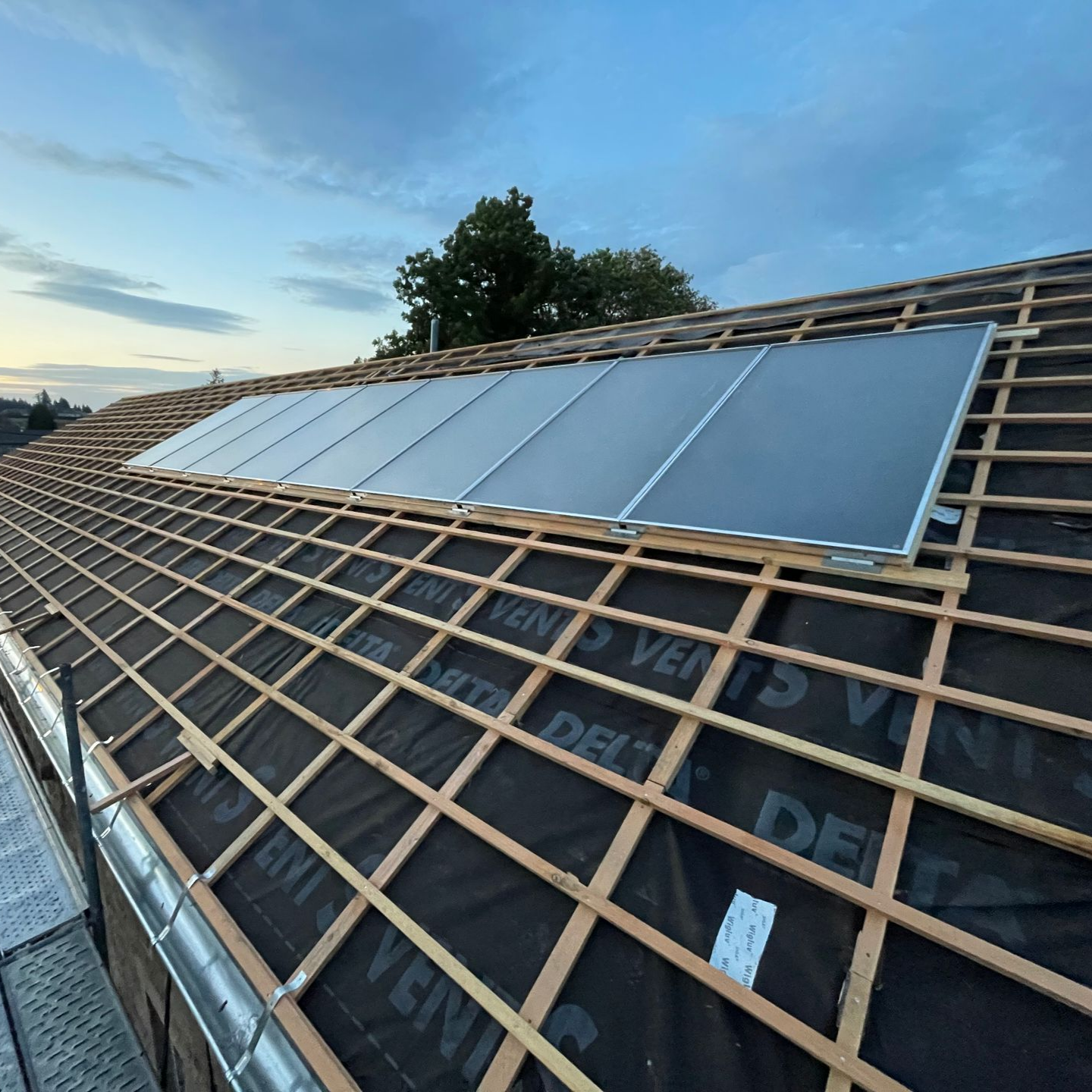 Panneaux solaires installés sur un toit partiellement en cours de construction.