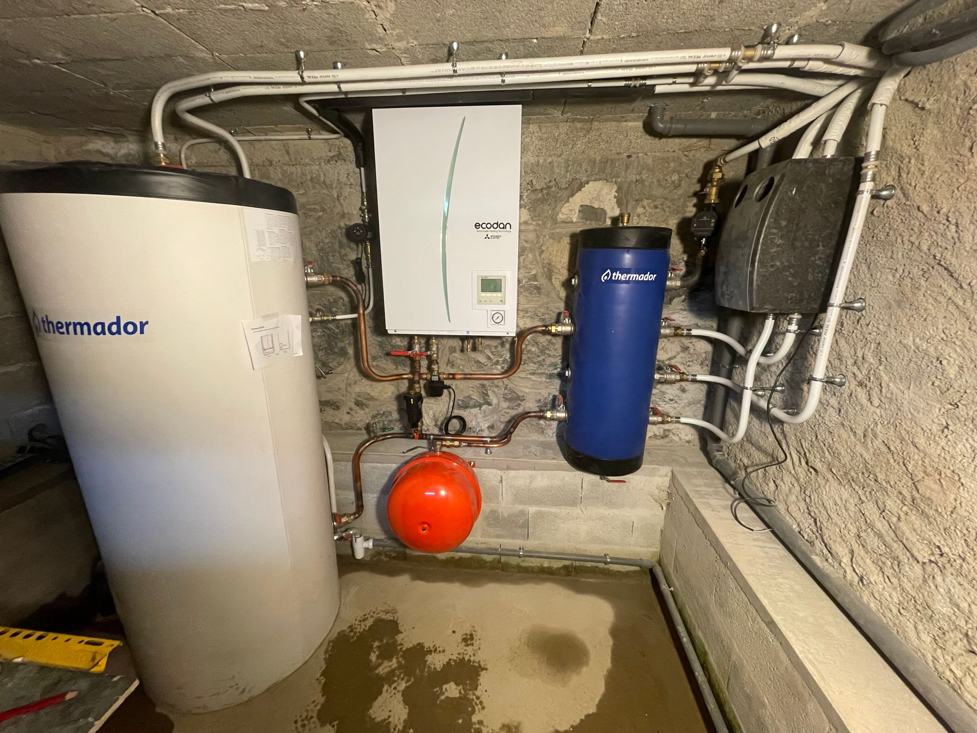 Système de chauffage composé d’une pompe à chaleur Mitsubishi Ecodan, d’un ballon de stockage Thermador et de plusieurs équipements hydrauliques installés dans une cave.