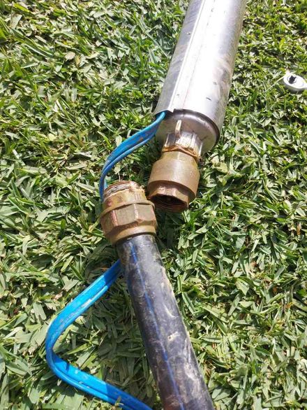 Manguera azul conectada a un accesorio de tubería metálica en el césped.