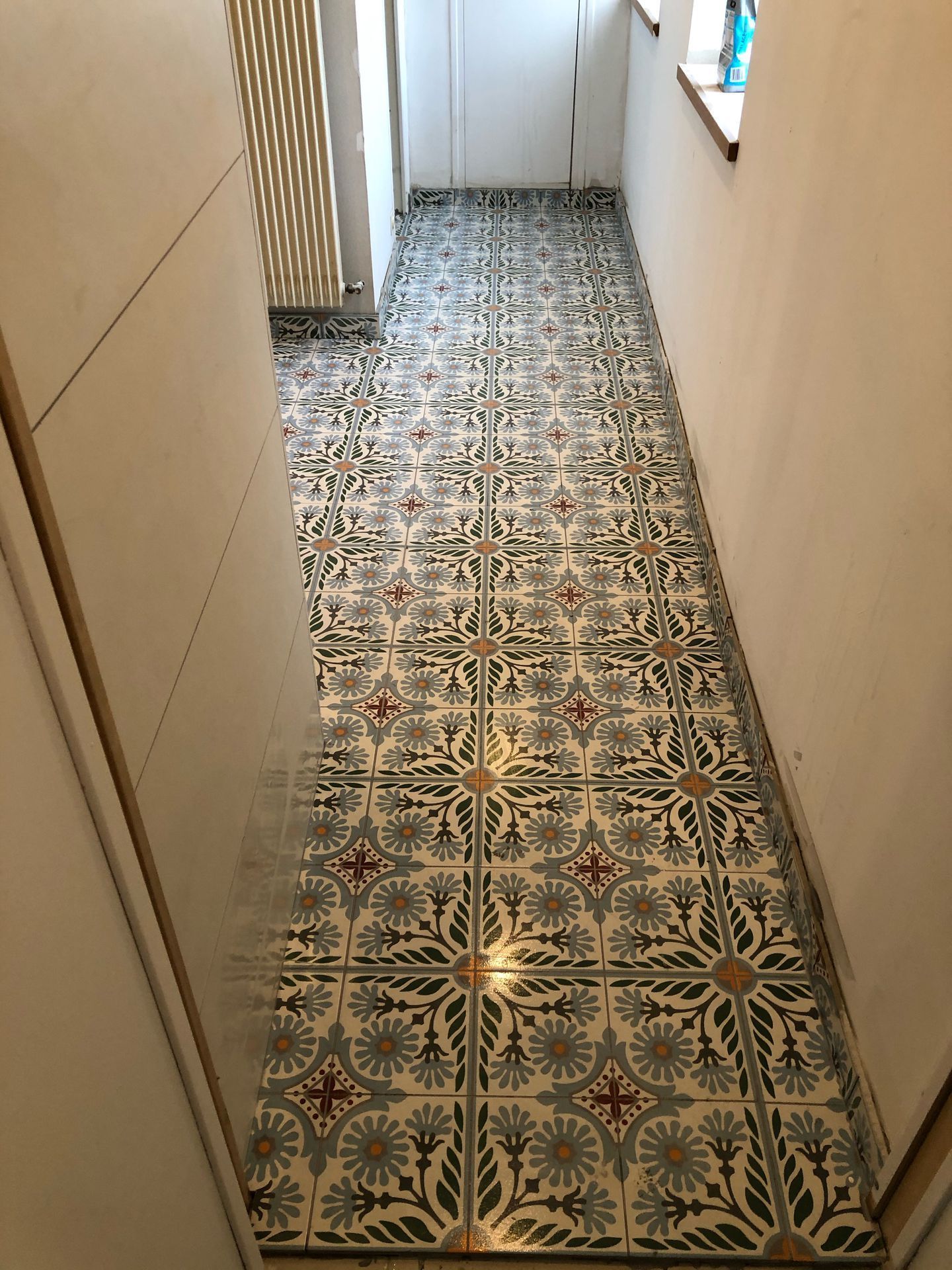 Du carrelage à motif au sol, dans un couloir.