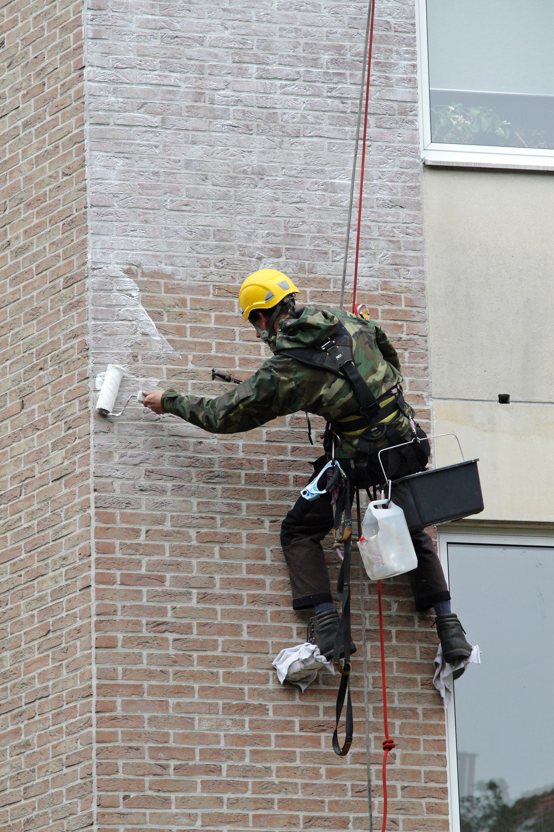 Une personne appliquant un traitement sur une façade poreuse.