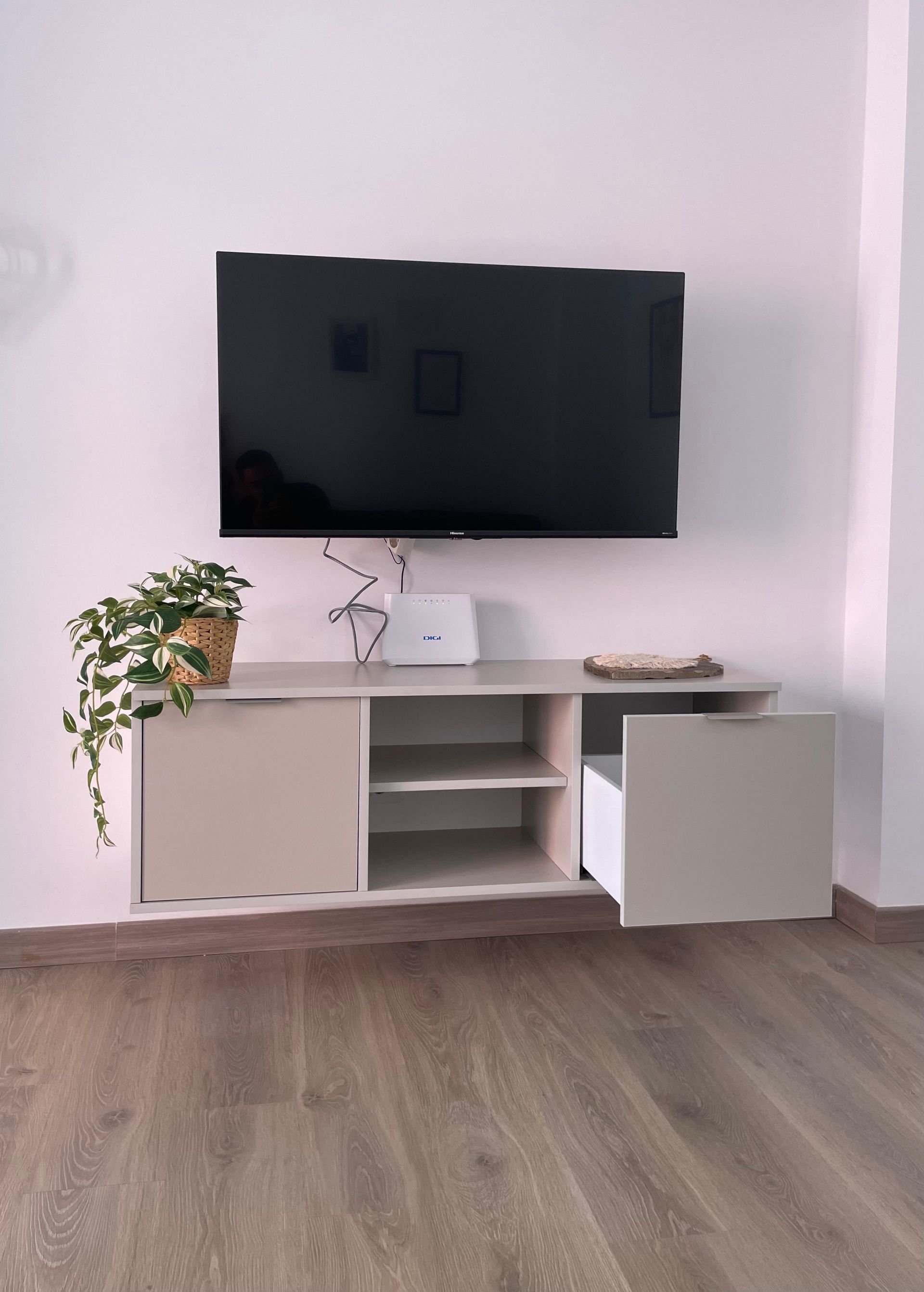 Un televisor de pantalla plana está montado en una pared encima de un centro de entretenimiento de madera.