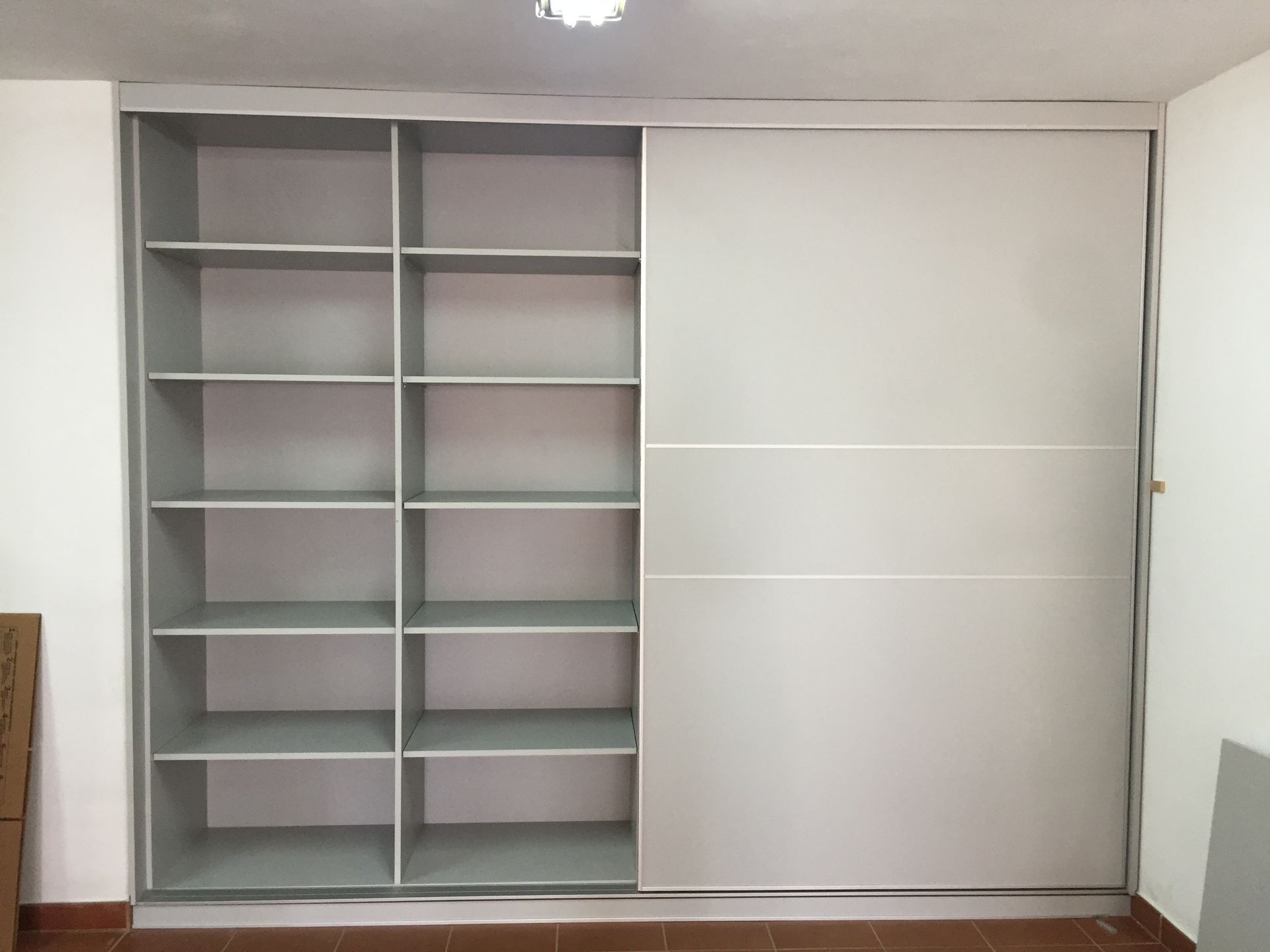 Un armario con puertas correderas y estantes en una habitación.