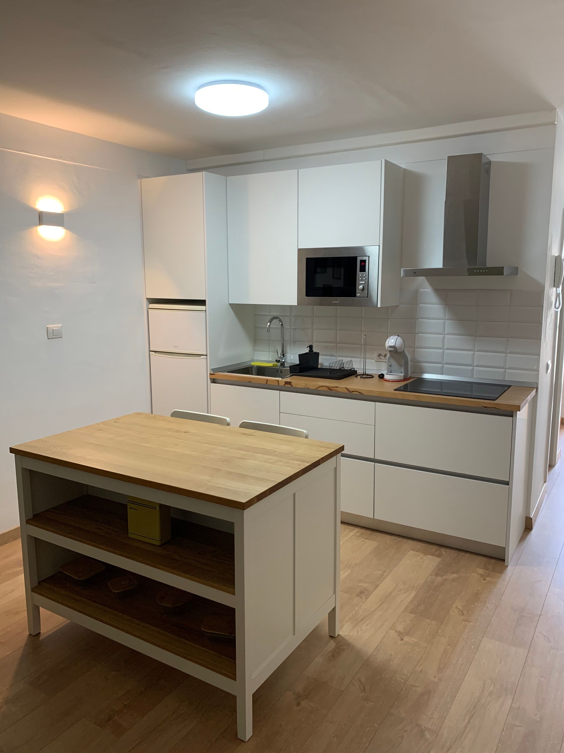 Una cocina con gabinetes blancos y una isla de madera.