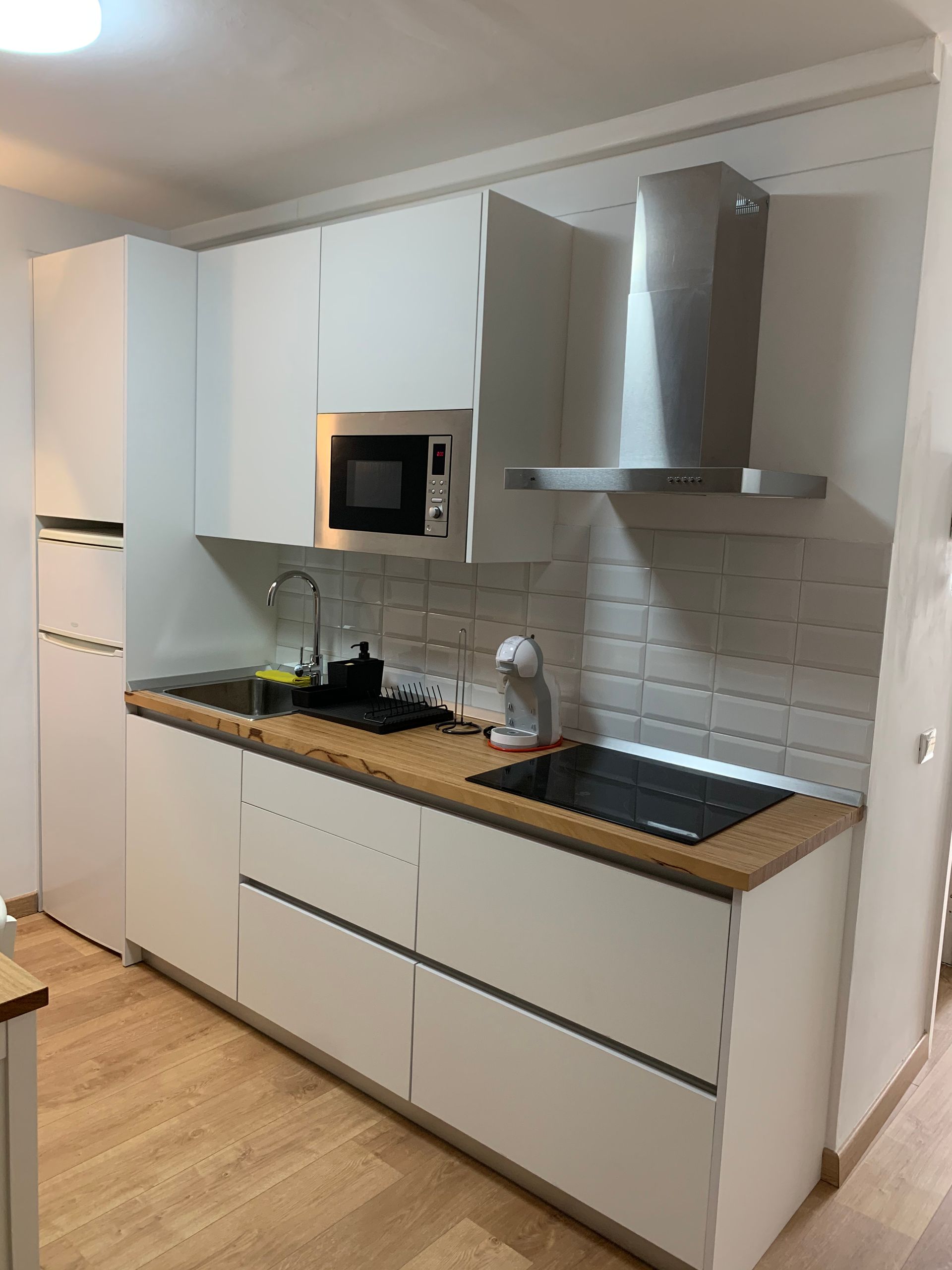 Una cocina con gabinetes blancos y encimeras de madera.