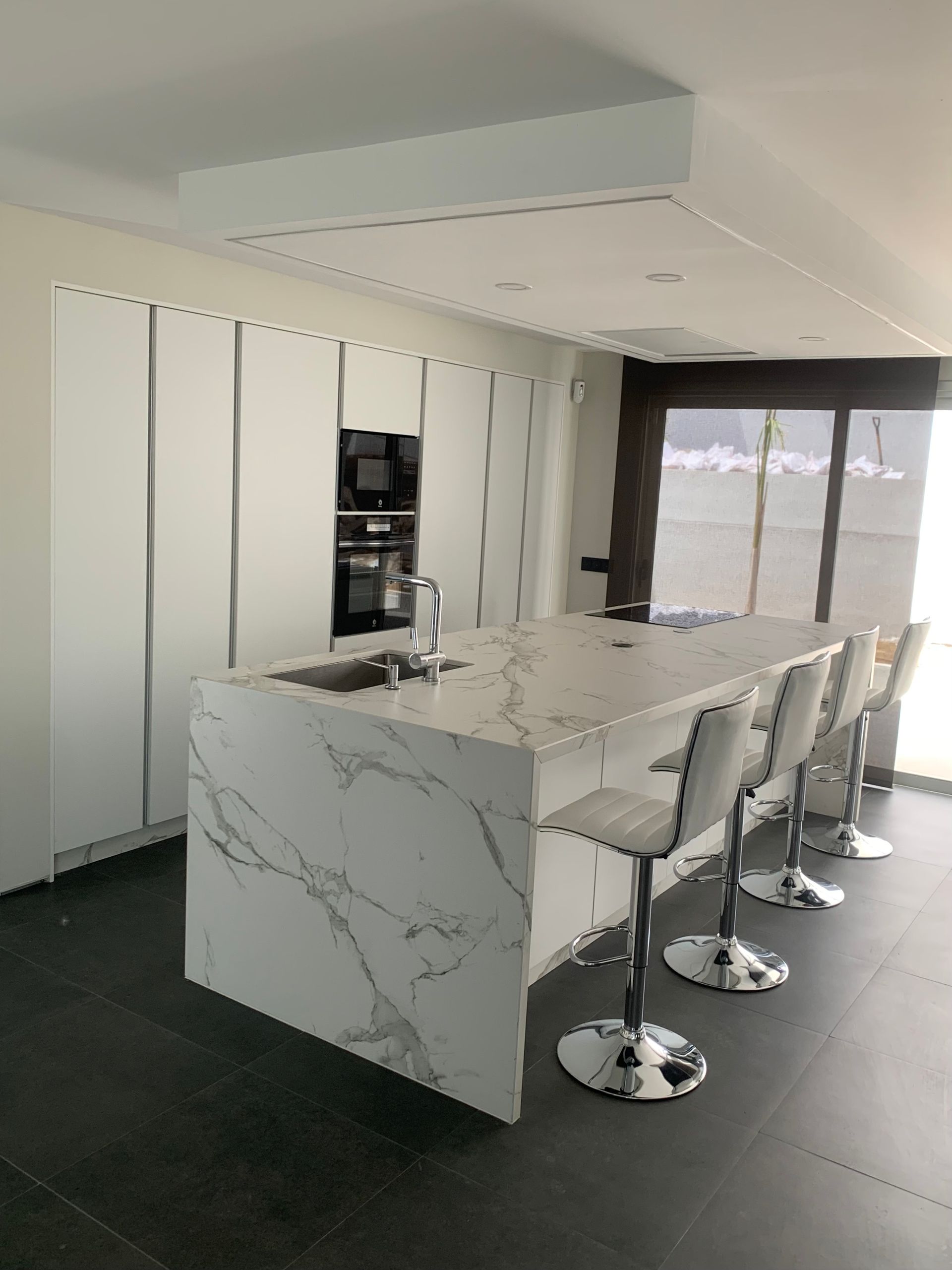 Una cocina con una gran isla y encimeras de mármol.