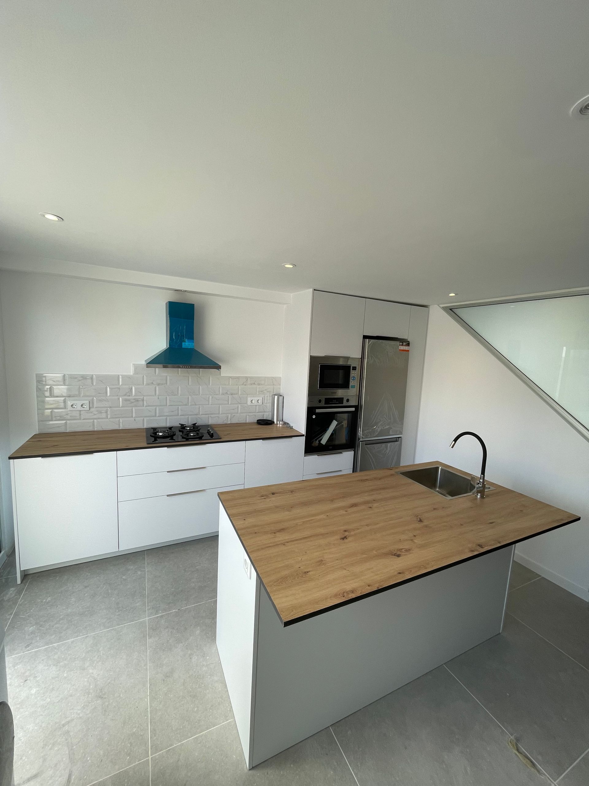 Una cocina con gabinetes blancos y una encimera de madera.